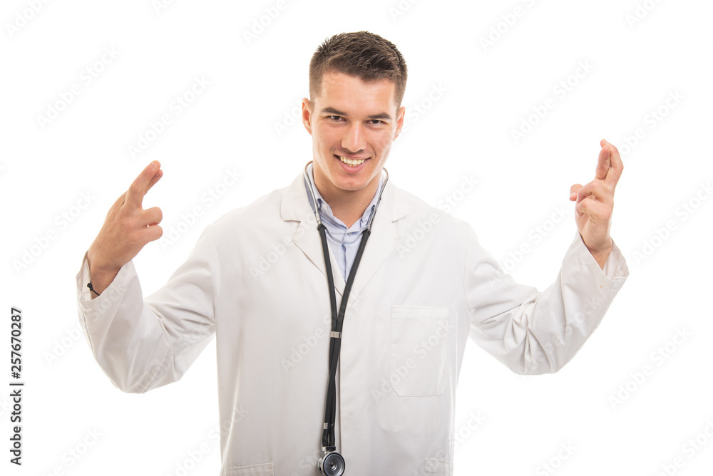 Portrait of young handsome doctor holding fingers crossed Portrait of young handsome doctor holding fingers crossed