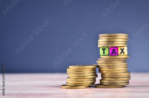 financial concept, colorful cube with word TAX and stacking coin on wooden table