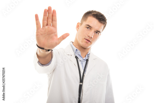 Portrait of young handsome doctor showing stop gesture