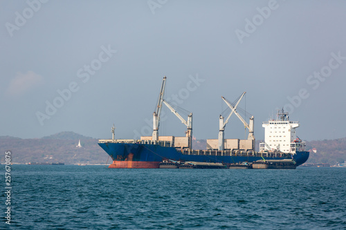 Container ship in export and import business and logistics. Shipping cargo to harbor by crane. Water transport International. Aerial view.Cargo ship carries the container heading to the port 