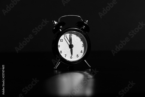 Black old style alarm clock isolated on black background. close-up