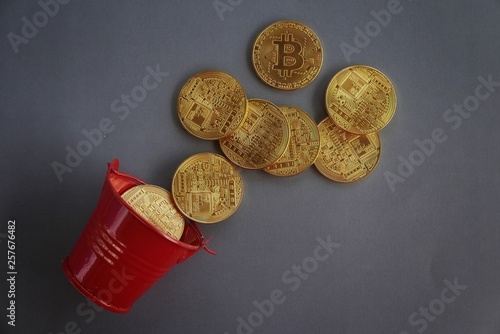 Red pile with golden replica of bitcoin on dark vignette grey background.