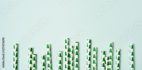 A pile of straws with Christmas trees image on a pastel background. Festive New year  long wide banner with copy space.