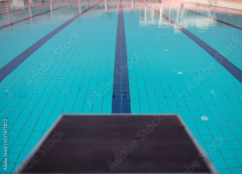 Starting blocks in row by the swimming pool, selective focus. Jump platform for swimming in swimming pool and grandstand background. Swimming pool with starting blocks. Sport facility. 