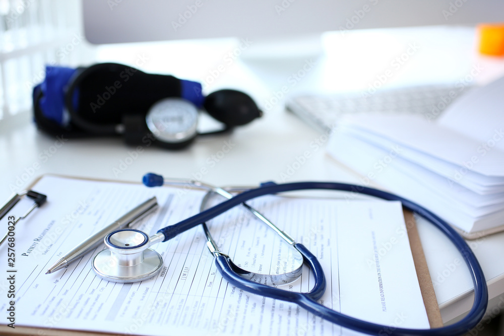 Stethoscope head and silver pen lying on medical application form