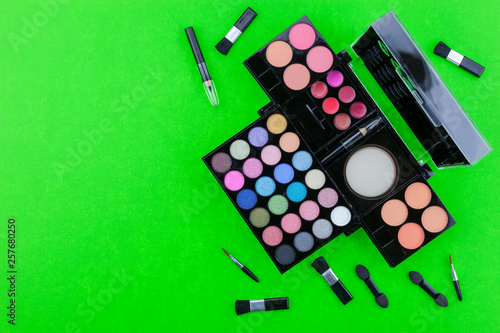 Flat lay photo of various makeup brush, eyeshadow and cosmetics on colorful paper background