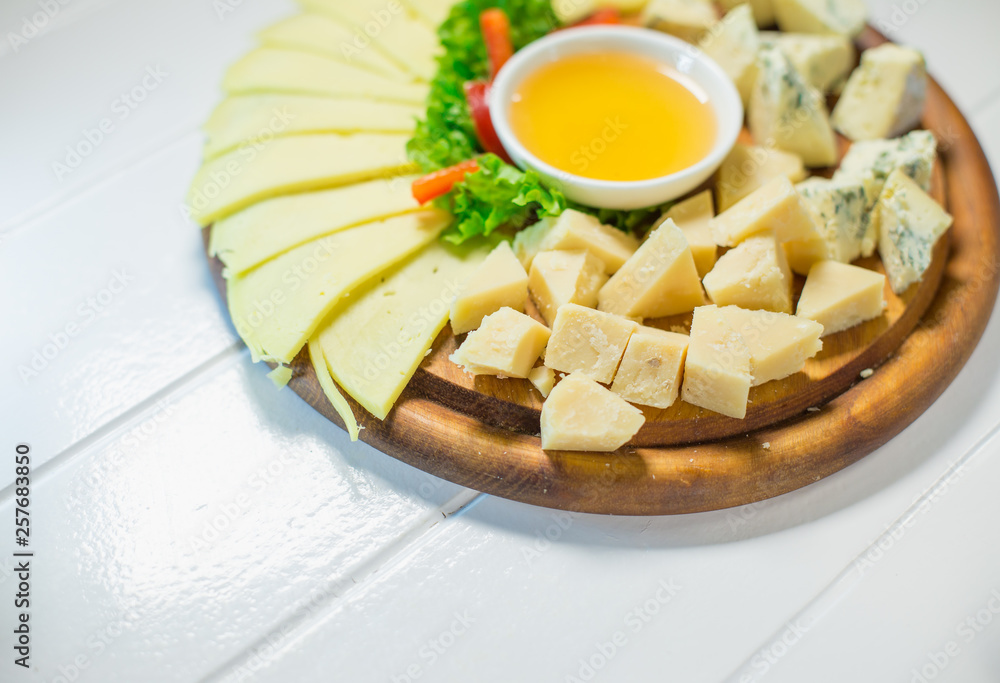 Delicious cheese on the table with honey and vegetables Delicious cheese on the table with honey and vegetables
