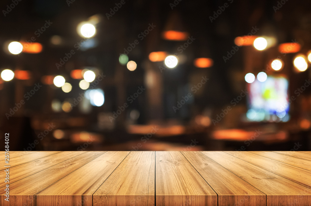 Empty wooden table top with blurred coffee shop or restaurant interior background. Abstract background can be used for display.