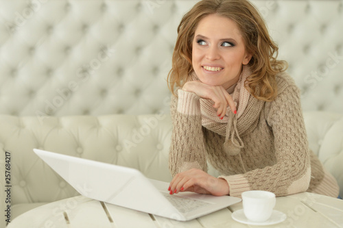 Portrait of beautiful young woman sitting at table and using laptop