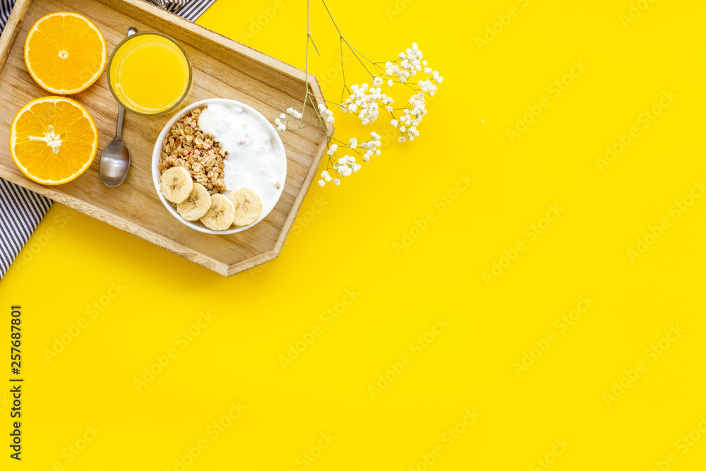 granola with banana slices and orange juice for breakfast on yellow background top view copyspace granola with banana slices and orange juice for breakfast on yellow background top view copyspace