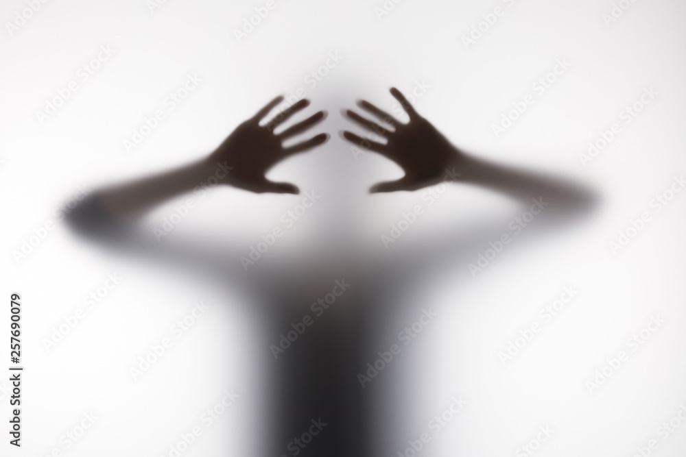 Blurry silhouette of person touching glass with hands Blurry silhouette of person touching glass with hands