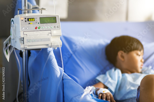 Obraz na plátně Close up adjust infusion pump set iv fluid intravenous drop saline drip with blurry patient boy in a hospital