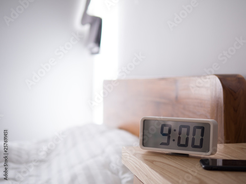 Digital alarm clock display 9 AM on the wood table,In the bedroom.