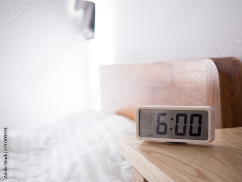 Digital alarm clock display 6 AM on the wood table,In the bedroom.