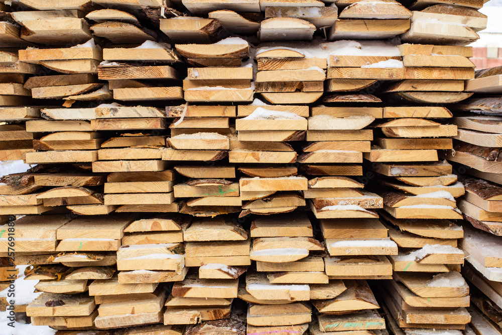Folded wooden brown and gray planks in a sawmill. Piled alder boards as texture Folded wooden brown and gray planks in a sawmill. Piled alder boards as texture