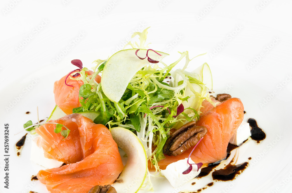 Marinated salmon with feta cheese, green apple, pecan and soy sauce on a plate on a white background Marinated salmon with feta cheese, green apple, pecan and soy sauce on a plate on a white background