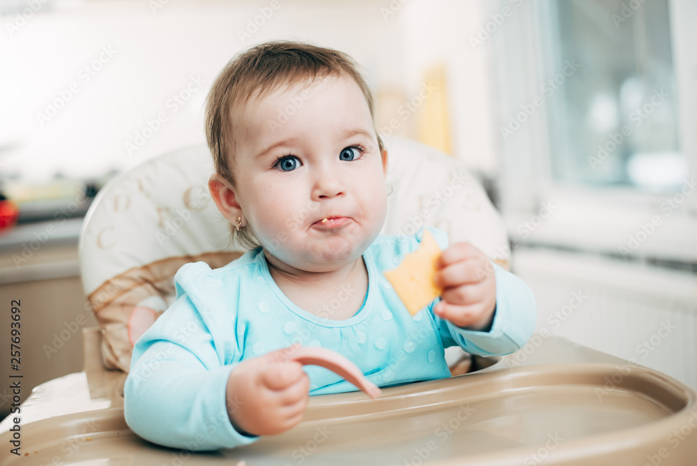 Little girl in a high chair eating cheese Little girl in a high chair eating cheese