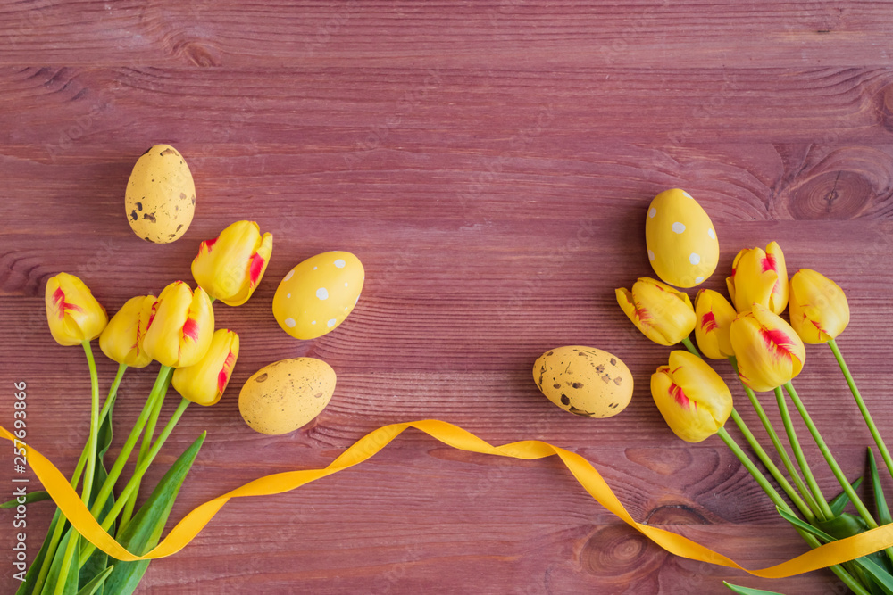 Flat lay composition with yellow tulips and easter eggs on a wooden background Flat lay composition with yellow tulips and easter eggs on a wooden background