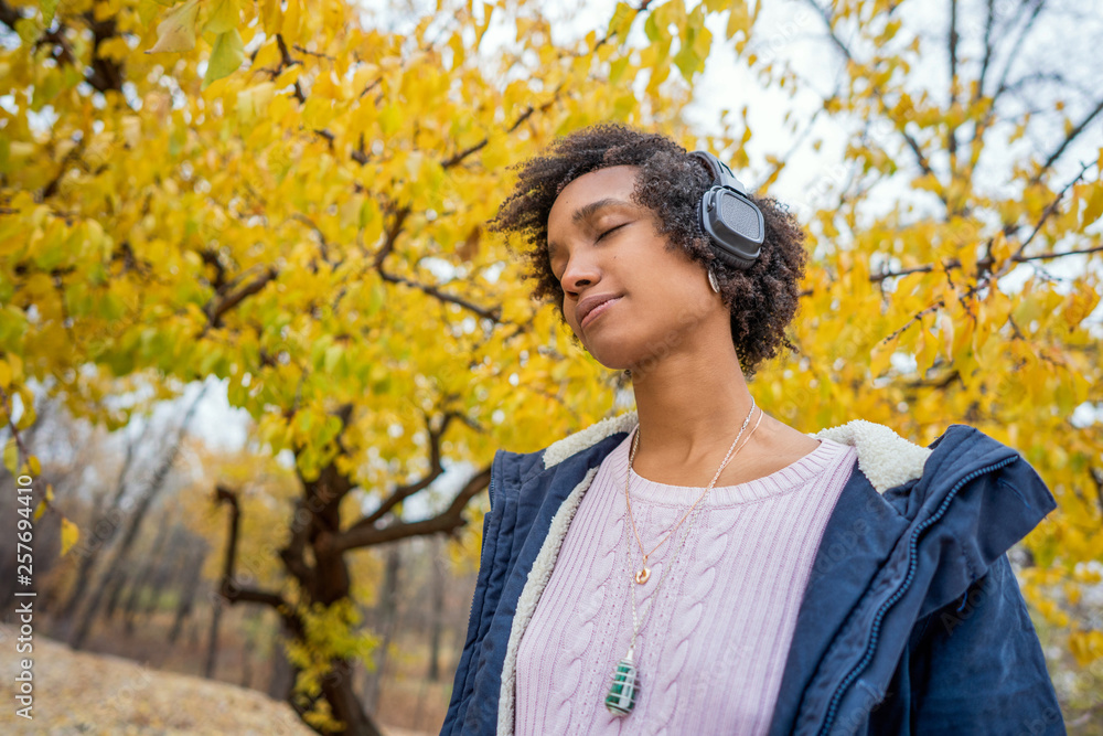 Afroamerican girl listening to music in the autumn at sunset