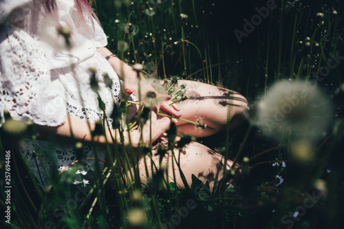the girl sitting in a high field with dandelions in the summer in the sun 