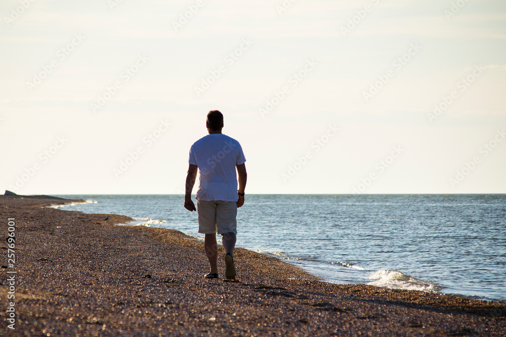 man walking along the beach. view from the back