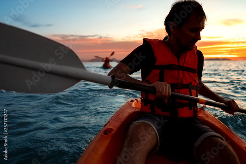 guy in kayaks in the sea at sunset