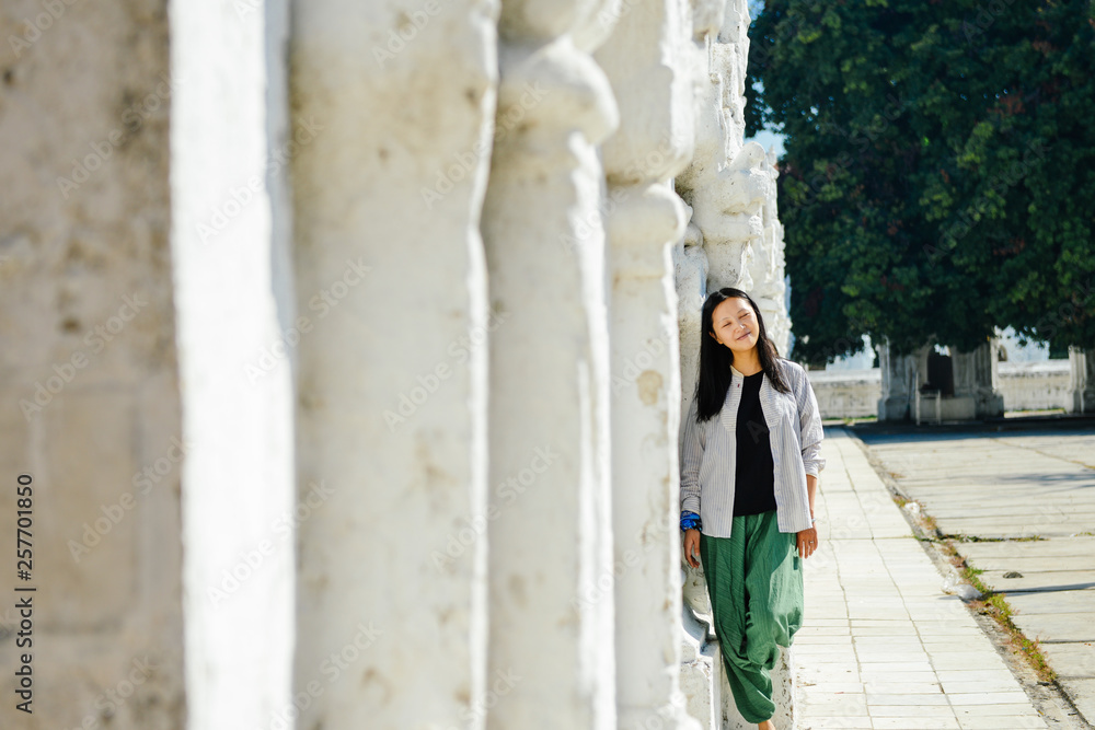 single Asian girl leans on white pagoda at Kuthodaw Pagoda, Mandalay, Myanmar