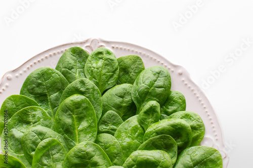 Young leaves of spinach on a plate. Copy space. Detox, a dietary food ingredient - green organic spinach.