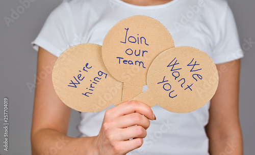Close up of  women  hand with 3  round paddles  shape cardboard paper   homemade with handwritten text  - We're Hiring, Join our Team, We want You .