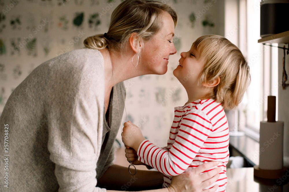 Mother and daughter rubbing noses in kitchen Mother and daughter rubbing noses in kitchen