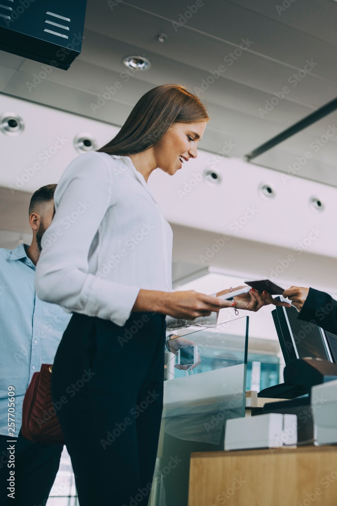 Low angle view of smiling young businesswoman checking in at airport Low angle view of smiling young businesswoman checking in at airport