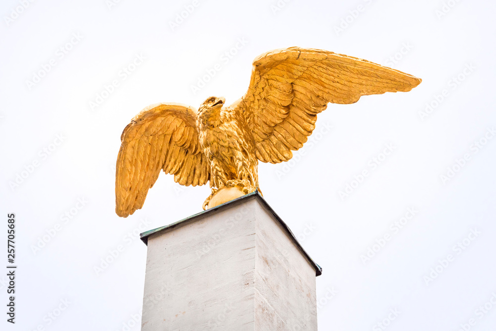 Golden eagle statue sculpture with spread wings on pedestal from below