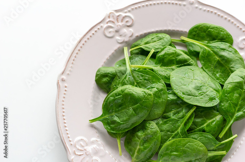 Young leaves of spinach on a plate. Copy space. Detox, a dietary food ingredient - green organic spinach.