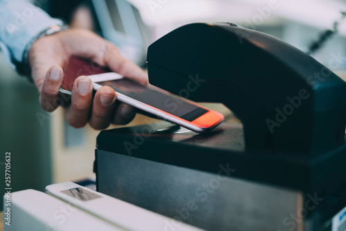 Cropped hands of businessman scanning ticket on smart phone at airport check-in counter photo