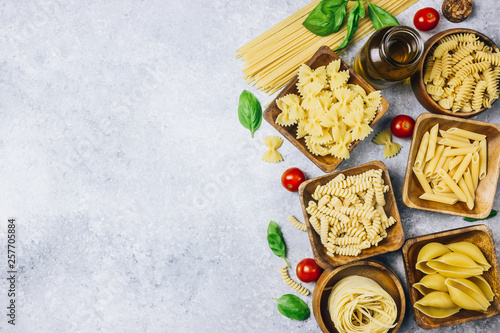 Various pasta on wooden bowls over light gray background