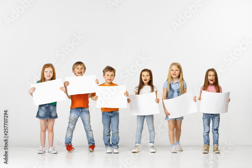 Group of happy smiling children with a white empty banners isolated in white studio background. Education and advertising concept