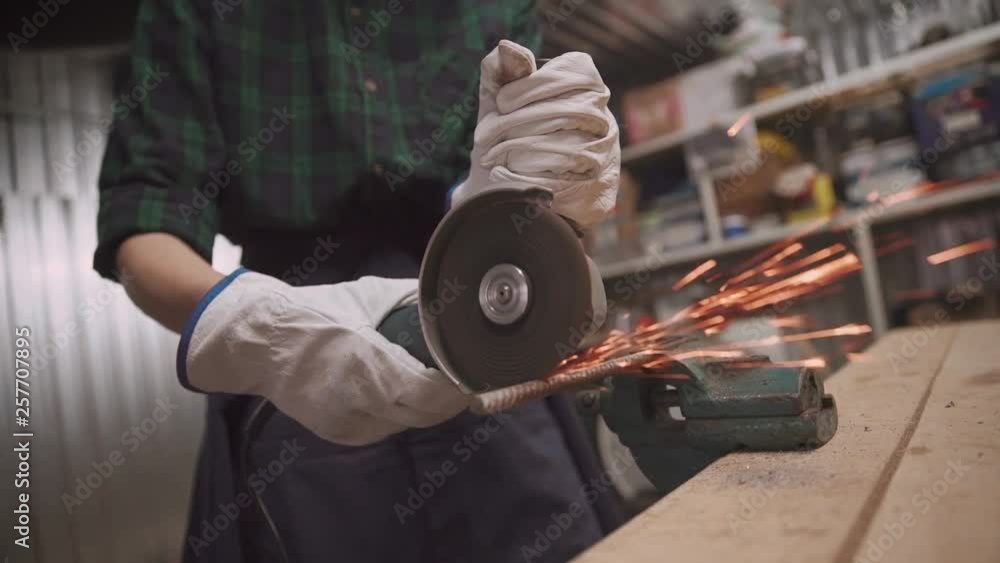 Closeup female hand cutting off pieces of iron bar with angle grinder. Slow motion Closeup female hand cutting off pieces of iron bar with angle grinder. Slow motion