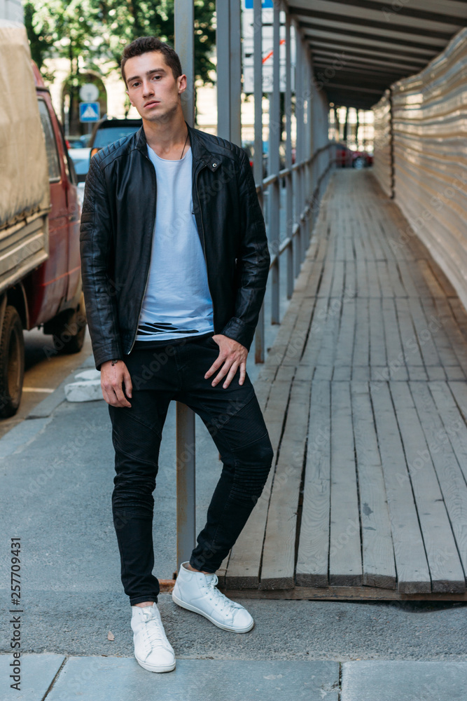 handsome, attractive guy, standing leaning on the railing in a white  T-shirt, black, leather jacket, black pants and white sneakers, moccasins,  sketchboards, Stock Photo | Adobe Stock