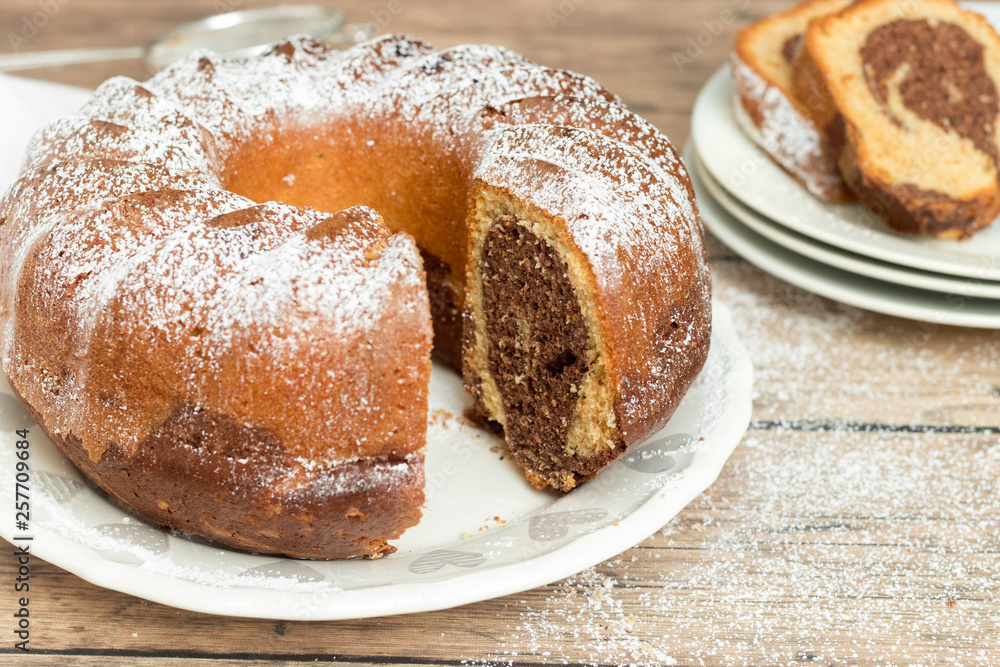 Marble cake with powdered sugar on top, wooden background Marble cake with powdered sugar on top, wooden background