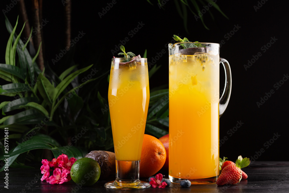 Mango lemonade - passion fruit in a jug and a glass and fruit on a dark wooden background Mango lemonade - passion fruit in a jug and a glass and fruit on a dark wooden background