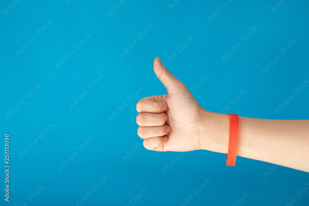 Female hand with empty red bracelet on blue background. Music festival branding empty wristband design. Clear sweat band mock up design.