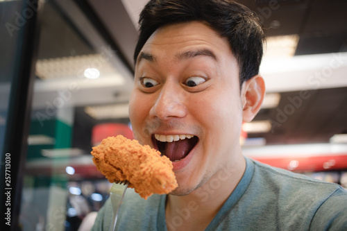 Funny face Asian man eat fried chicken. photo