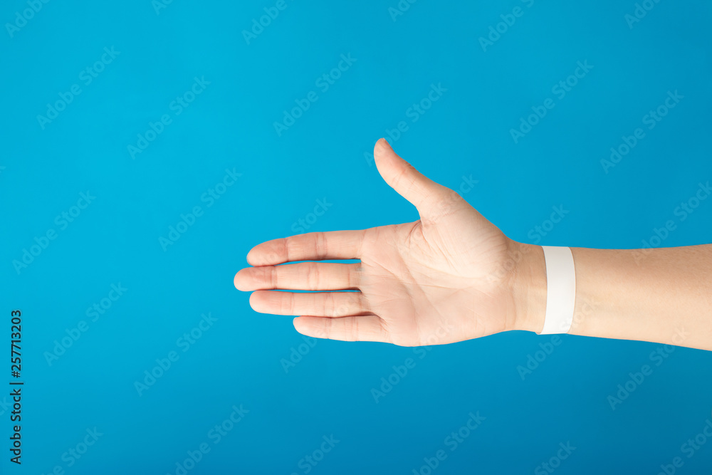 Female hand with empty paper white bracelet on blue background. Music festival branding empty wristband design. Clear sweat band mock up design.