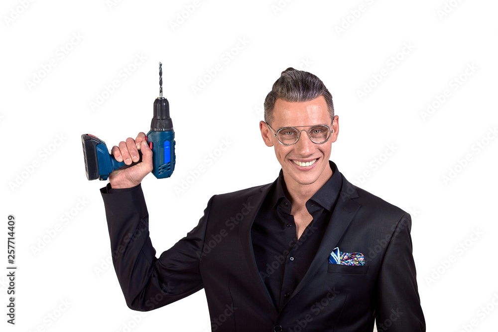 Portrait of crazy funny young man in black suit smiling at camera with a drill holds at his temple. indoor studio shot. Fuck the brain Portrait of crazy funny young man in black suit smiling at camera with a drill holds at his temple. indoor studio shot. Fuck the brain