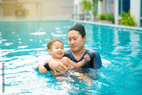 Child boy learn swimming with mom in swimming pool