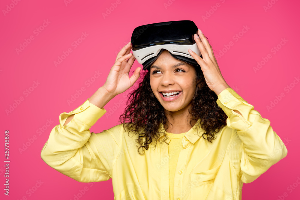 happy curly african american woman wearing virtual reality headset and smiling isolated on crimson happy curly african american woman wearing virtual reality headset and smiling isolated on crimson