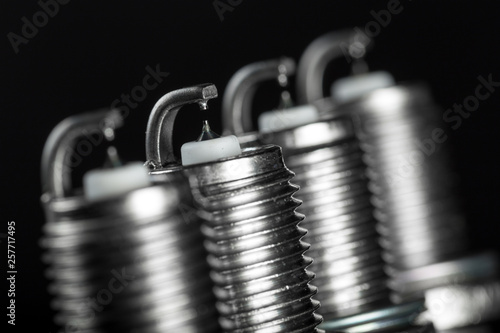 A set of new spark plugs of the car, and spare parts of vehicles on a dark background.