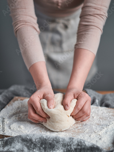 Woman hands kneading a bread dough on a wooden board