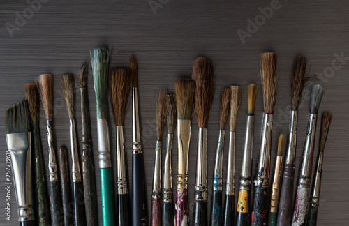 Old used small paint brushes on brushed metal texture background