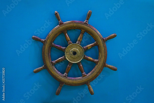Old wooden ship wheel on blue background